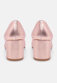 Rose gold faux leather heels with a rounded toe and a wide block heel. The surface has a metallic finish and a smooth texture.