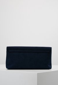 Modrý semišový psaníčko s obdélníkovým tvarem a klopou na zavírání. Hladká textura s jemným prošíváním podél okraje.