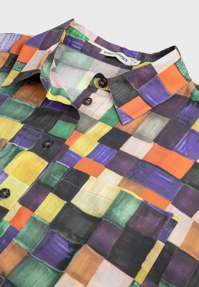 Chemise colorée à manches courtes avec un motif à carreaux dans les tons de violet, vert, orange et noir, dotée d'un col classique et d'une fermeture à bouton.