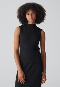 Zwarte mouwloze top met een hoge hals, textuurstof en een licht aansluitende silhoutte, met een subtiele plooidetail bij de schouder.