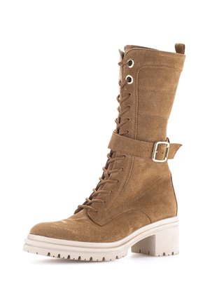 Tan suede lace-up ankle boot with chunky white sole, block heel, and adjustable buckle strap around the upper shaft.