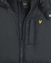 Marineblå puffjakke med teksturert finish, frontglidelås og en liten, brodert logo i gult. Den har hette og brystlomme.