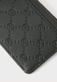 Black textured cardholder with embossed circular patterns and dotted accents, featuring a stitched edge for durability.