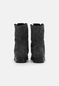 Bottes chevilles en daim gris foncé à texture lisse, bout arrondi et petit talon noir. Aucun fermoir ni ornement visible.