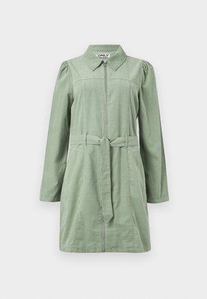 Vaaleanvihreä, pitkähihainen mekko, jossa on kaulus, etuvetoketju, vyö vyötäröllä ja hieman puffatut olkapäät, yksinkertaisella taustalla.