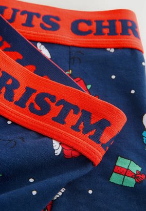 Mörkblått tyg med röd midjerem som har mörkblå texten "CHRISTMAS" och julmotiv som presenter och snöflingor.