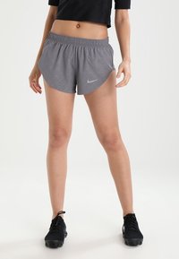 Grå träningsshorts med ett diamantmönster, elastisk midja och en liten Nike-logga framtill, i kombination med svarta träningsskor.