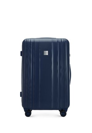 Navy hard-shell suitcase with a textured surface, vertical grooves, retractable handle, and four spinning wheels for easy mobility.