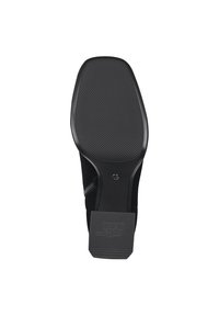 Suela de zapato negra con una superficie texturizada. Presenta una forma curvada y una suela de goma. Logo estampado en el talón, con detalle de costura en los laterales.