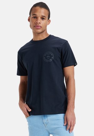 Granatowa bawełniana koszulka z krótkim rękawem i okrągłym dekoltem. Posiada logo w okrągłym wzorze na lewej części klatki piersiowej.