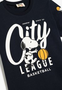 Granatowy bawełniany t-shirt z grafiką Snoopy'ego grającego w koszykówkę, z białym napisem "City League Basketball" i pomarańczową piłką do koszykówki.