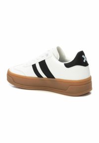 Sneaker bianco con strisce nere e un accento nero sul tallone. Presenta una tomaia testurizzata e una suola in gomma naturale. Design pulito con chiusura con lacci.