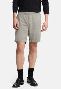 Shorts gris clair en mélange de coton, dotés d'une taille élastique, de poches latérales et d'une coupe décontractée, se terminant juste au-dessus du genou.