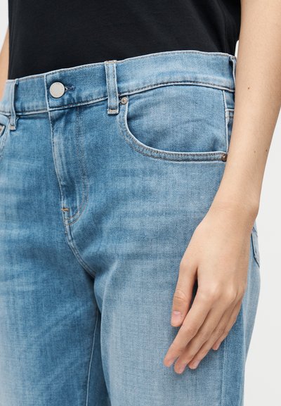 Ljusblå denimjeans med en lätt blekt yta, utrustade med en metallknapp, fickor och synliga sömdetaljer.