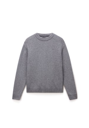 Suéter gris de tejido de punto suave, con un escote redondo, mangas largas y puños y dobladillo acanalados. Pequeño logotipo en el pecho.