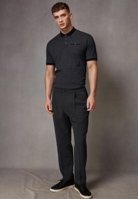 Tee-shirt polo cu model naval, cu guler, asortat cu pantaloni gri tip tailored și adidași negri. Ținuta prezintă accente și texturi subtile.