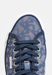 Sneaker in tela blu con motivo a trama, lacci blu navy, occhielli d'argento e suola in gomma bianca. Logo Calvin Klein sul lato.