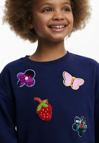 Felpa navy con applicazioni ricamate multicolori: farfalla rosa, fragola rossa e due fiori in paillettes e tessuto.