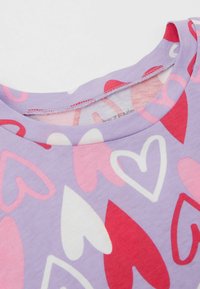 Lila Baumwoll-T-Shirt mit einem verstreuten Herzmuster in Pink, Rot und Weiß. Runder Ausschnitt und weicher Stoff.