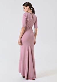 Abito aderente con maniche a campana in morbido tessuto rosa; presenta un'apertura a chiave sul retro e un orlo svasato. Tessuto liscio con un leggero drappeggio.