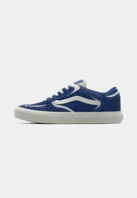 Blue suede sneaker with white accents, padded collar, and rubber sole. Features a classic lace-up design and perforated detailing on the sides.