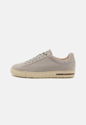 Sneakers in suede grigio chiaro con lacci tonalizzati. Presentano una suola in gomma beige e una texture sottile. Design semplice con accenti minimi.