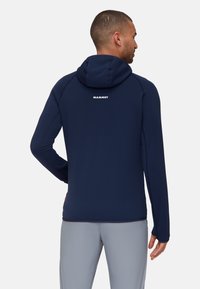 Felpa blu navy con design aderente, caratterizzata da un collo alto, cappuccio con cordino e dettaglio del logo sul retro. Tessuto elastico e liscio.