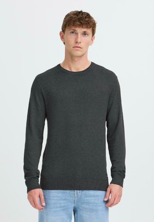Suéter de punto gris oscuro con mangas largas, cuello redondo y puños acanalados. Combinado con jeans de mezclilla azul claro.