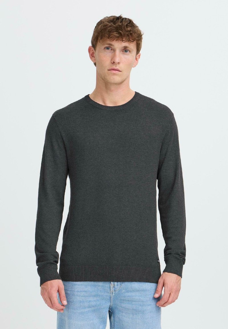 Suéter de punto gris oscuro con mangas largas, cuello redondo y puños acanalados. Combinado con jeans de mezclilla azul claro.