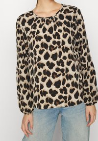 Leoprint-Oberteil mit rundem Halsausschnitt, langen Ärmeln und Raffung an den Schultern. Hergestellt aus leichtem Stoff mit glatter Textur.