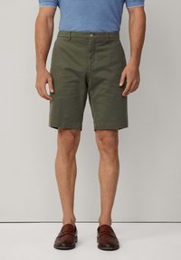 Khaki shorts lavet af bomuld, skræddersyet pasform, knælængde, med en frontknaplukning og to sidelommer. Båret med brune loafers.