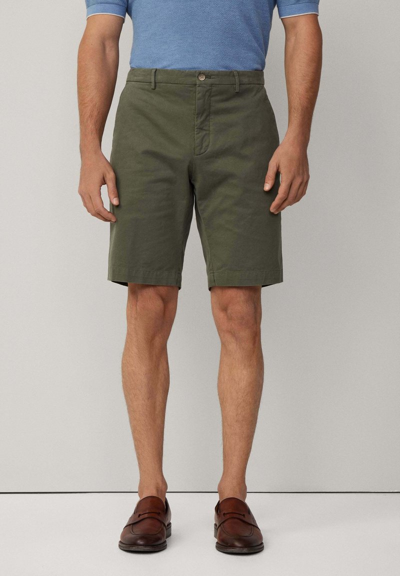 Khaki shorts lavet af bomuld, skræddersyet pasform, knælængde, med en frontknaplukning og to sidelommer. Båret med brune loafers.