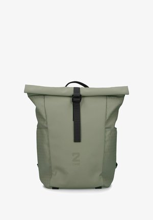 Sac à dos à rabat en vert olive, avec côtés texturés, sangle noire et bouclerie, et accents à motif triangulaire sur les poches.