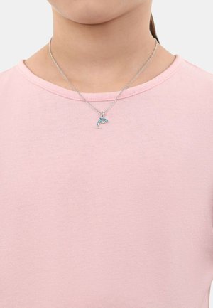 Collana d'argento con un ciondolo a forma di delfino; indossata su una maglietta rosa chiaro a maniche corte con collo rotondo; tessuto dalla texture liscia.