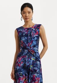 Abito senza maniche con dettaglio frontale arricciato, caratterizzato da un motivo floreale blu e colorato, realizzato in tessuto leggero con una consistenza liscia.
