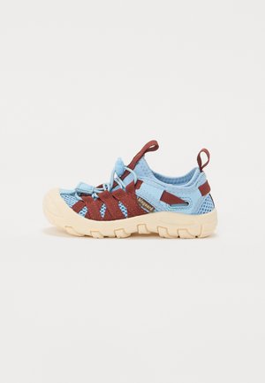 Scarpe in rete azzurro chiaro con cinturini rosso scuro, dotate di una suola spessa beige e di una linguetta sul tallone per una facile calzata.