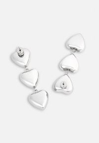 Srebrne kolczyki w kształcie serca, trzy połączone serca, polerowana powierzchnia, zapięcie na sztyft, gładka tekstura, refleksyjny wykończenie, nowoczesny design.