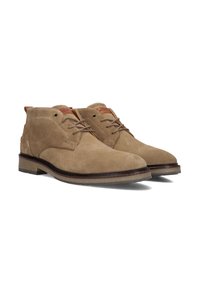 Bottines en daim beige avec un design à lacets, semelle en caoutchouc et accents en cuir contrastants près du col. Texture douce, bout arrondi.