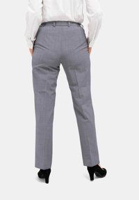 Lichtgrijze, op maat gemaakte broeken met een gestructureerd patroon, rechte pijpen en een elastische tailleband, gecombineerd met zwarte hoge hakken.