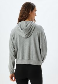 Sudadera gris recortada con capucha ajustable, que cuenta con mangas largas y un corte relajado. Fabricada con una suave tela texturizada.