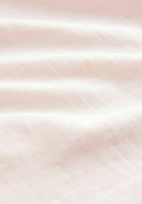 Jasnoróżowa tkanina o miękkiej fakturze, z delikatnymi falami i jednolitym wzorem splotu, tworząca gładki wygląd.