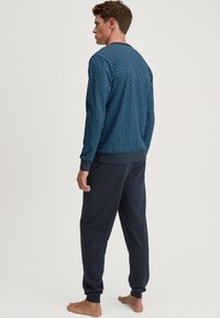 Navyblauw sweatshirt met een geometrisch patroon, gecombineerd met donkere jogpants, beide gemaakt van zacht, ademend materiaal.