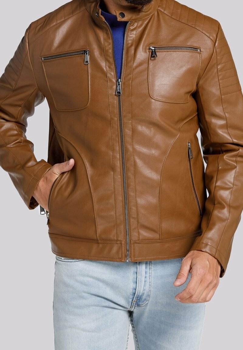 Giubbotto in pelle marrone con colletto alto, due tasche sul petto con zip, tasche laterali e dettagli in quilt sulle spalle. Texture liscia.