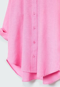 Camisa de botón rosa claro con una textura suave, dobladillo curvo y seis botones a juego en el frente. Presenta mangas enrollables.