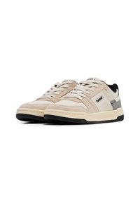 Sneakers bege e creme com materiais de camurça e couro, apresentando um colarinho almofadado, atacadores planos e uma sola em borracha preta.
