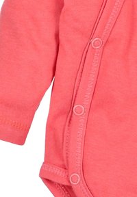 Koralli vauvan body, joka on valmistettu pehmeästä puuvillasta, jossa on pitkät hihat, napitus ja sileä pinta.