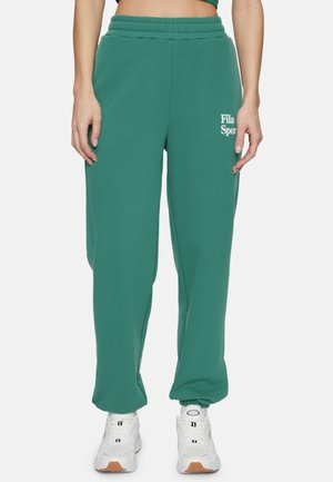 Groene katoenen sweatpants met een elastische tailleband, voorzien van een wit "Fila Sport" logo. Losse pasvorm die naar de boorden toe taperd, gecombineerd met witte sneakers.