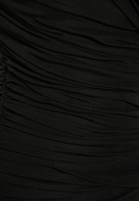 Robe noire avec un tissu froncé et texturé, doté de plis horizontaux. Le matériau semble extensible et lisse, créant une silhouette ajustée.