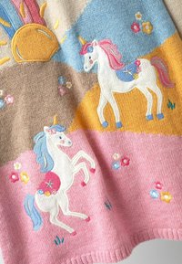 Strickdecke mit Einhornmotiven in Weiß, Rosa und Blau mit floralen Akzenten. Der Hintergrund besteht aus pastellfarbenen Blockmustern: Beige, Blau und Rosa.