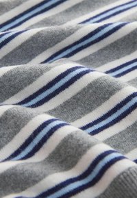 Tissu doux avec des rayures horizontales en gris, blanc, bleu foncé et bleu clair, présenté en gros plan avec des plis doux.